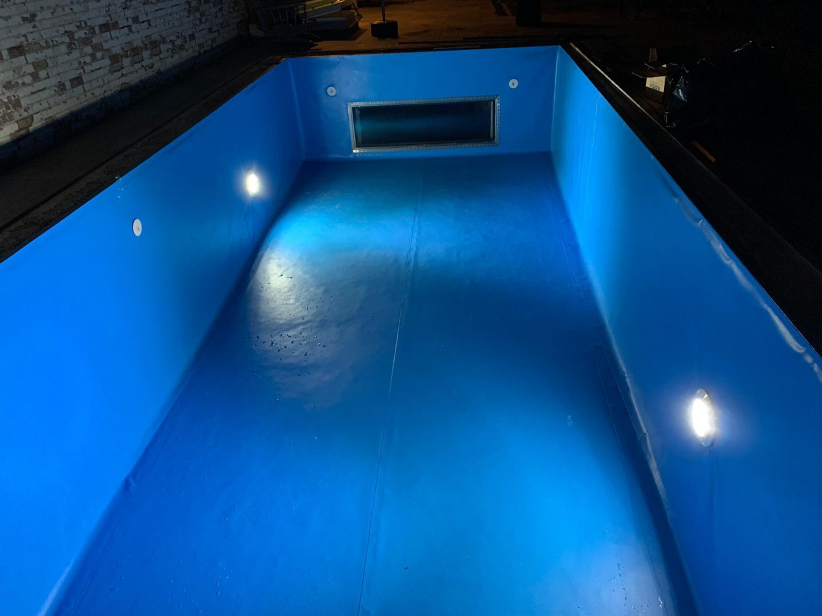 Piscina 7x3m en lámina azul con ventana de cristal al salón en Castrillo del Val